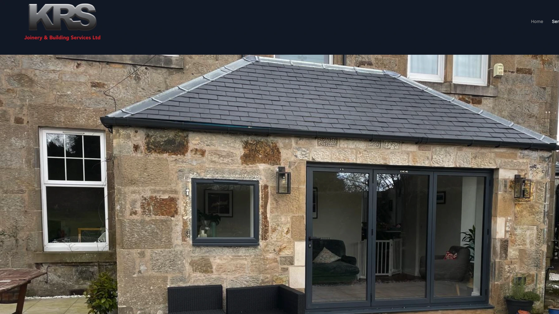Homepage of KRS Joinery and Building Services, a stone extension with bi-fold doors under a dark navy header